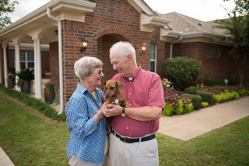 Couple with dog outside of their house