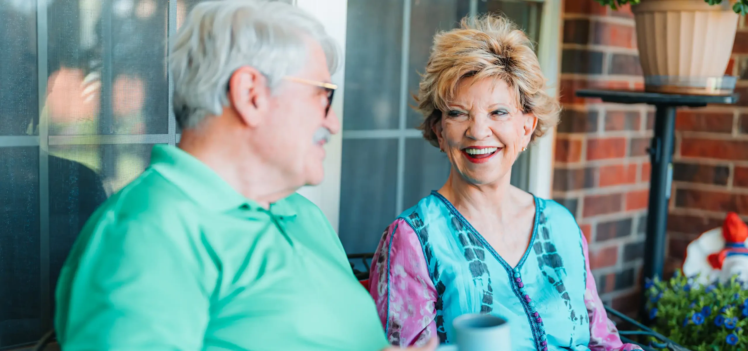 A senior couple talk on the porch